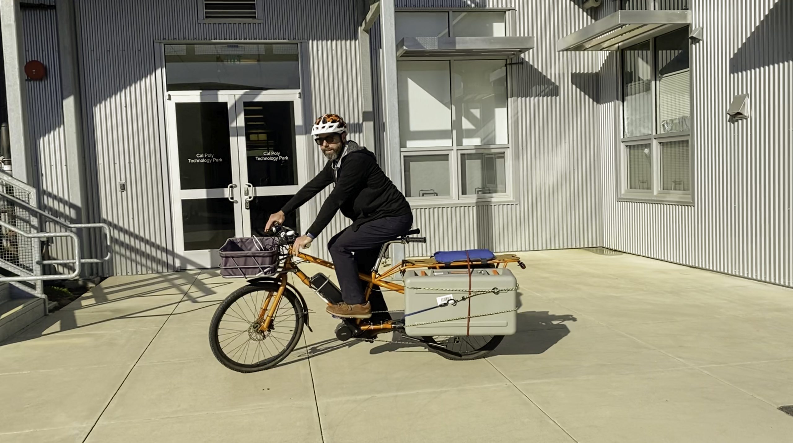 A picture containing a man riding a bicycle with a snowball edge on the bike